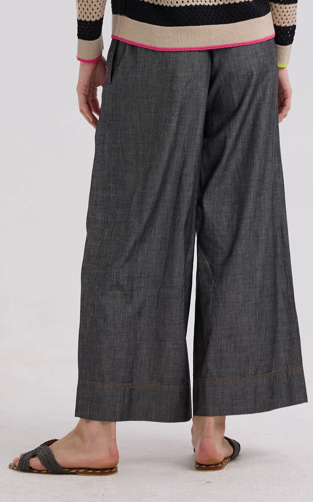 Person wearing wide-leg gray pants on a white background