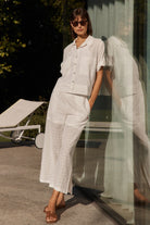 Woman in a white outfit standing outdoors with blurred background