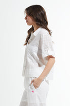 Woman wearing a white outfit with a textured pattern on a white background