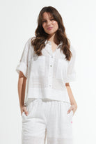 Woman wearing a white outfit with a textured pattern on a white background