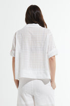Person wearing a white textured shirt and pants on a white background back