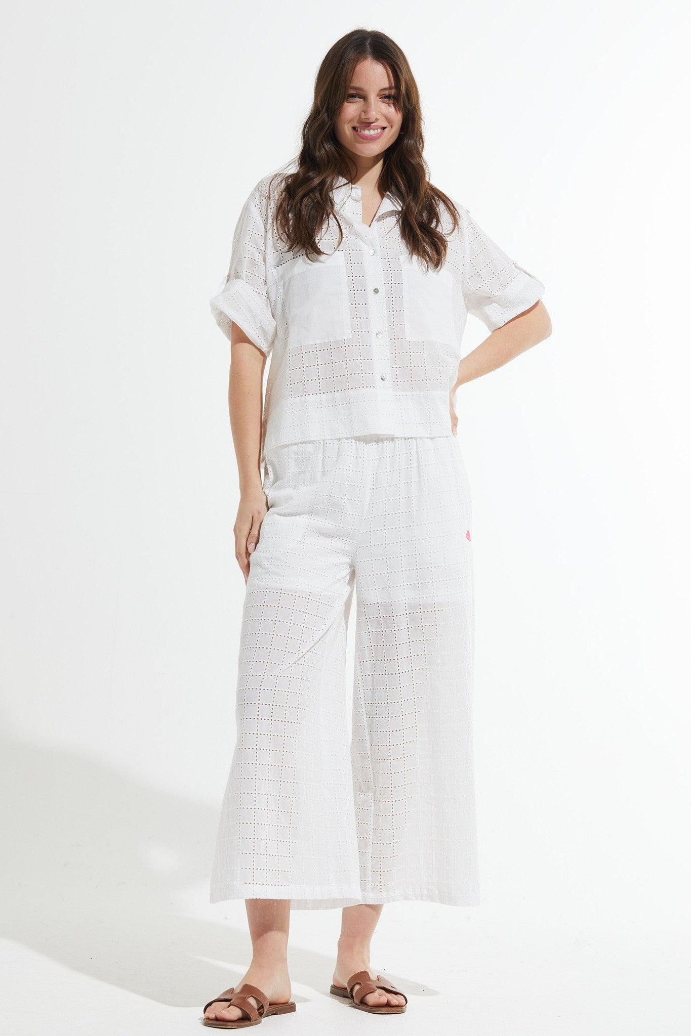 Woman wearing a white outfit with wide-leg pants on a white background