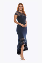 Woman wearing a navy blue dress with patterned overlay on a white background