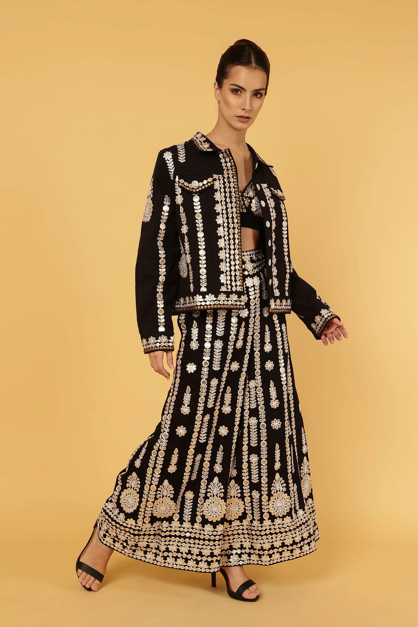 Woman wearing a black and gold patterned outfit on a yellow background