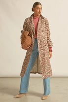 Woman wearing a leopard print coat with a plain background