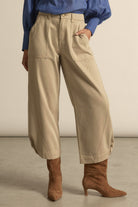 Person wearing beige pants and brown boots against a neutral background