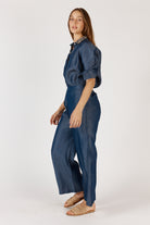 Women wearing a denim shirt and pant set on a white background side on view
