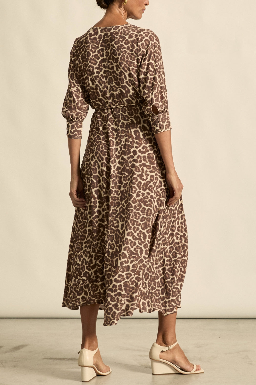 Woman wearing a leopard print dress against a neutral background