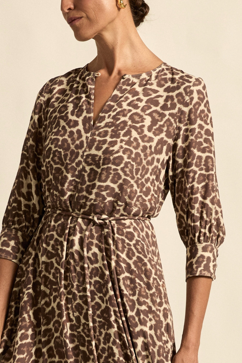 Woman wearing a leopard print dress against a beige background
