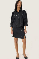 Woman wearing a black outfit with pearl embellishments on a white background