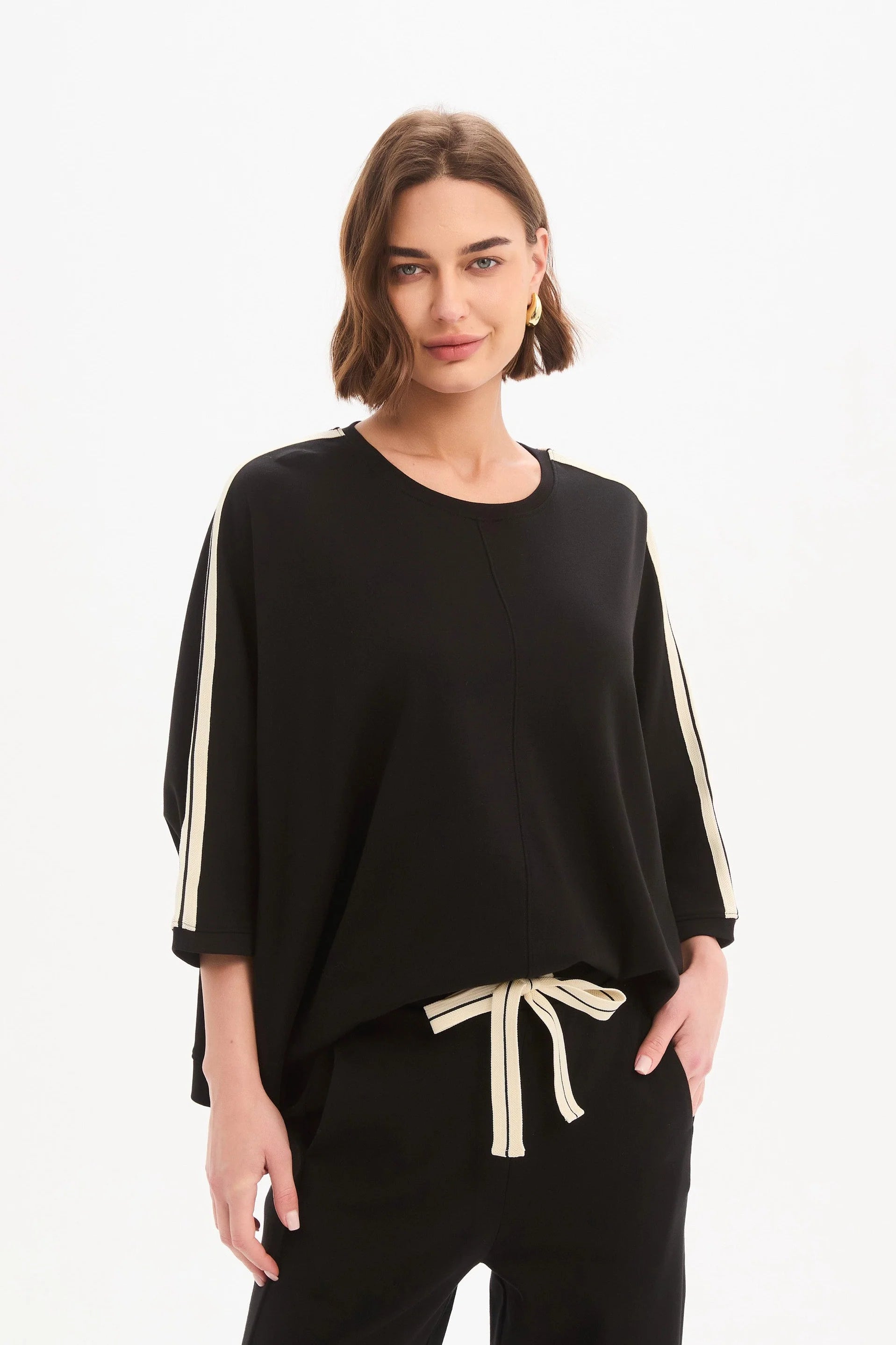 Woman wearing a black outfit with white stripes on a white background