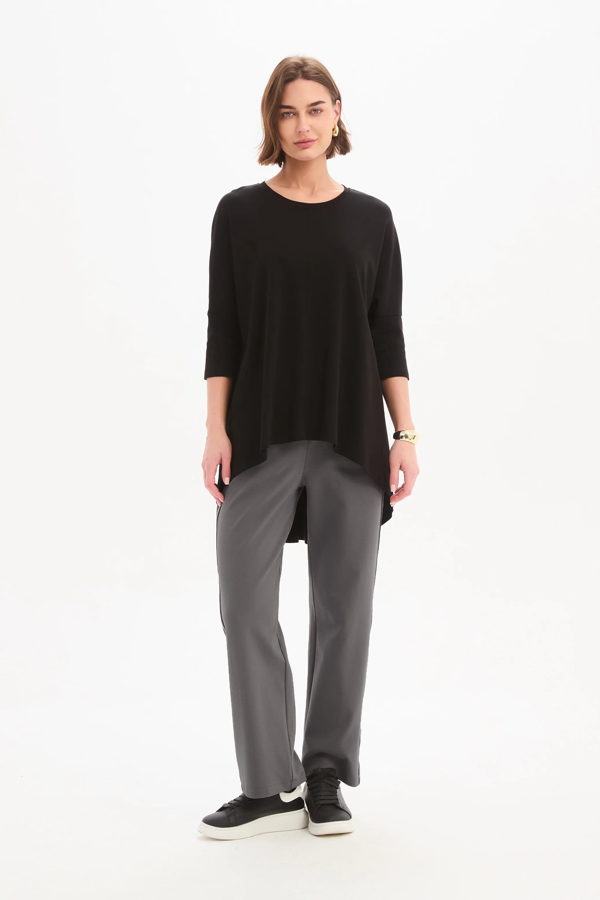 women wearing a black top and grey pants on a plain background