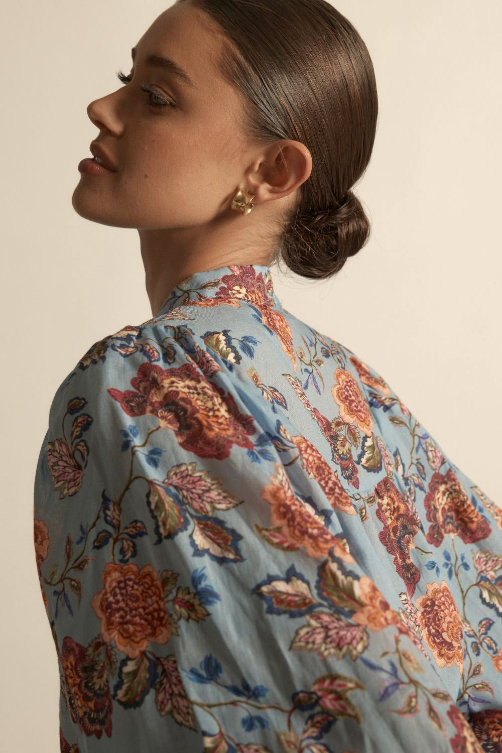Woman wearing a floral blouse with a neutral background
