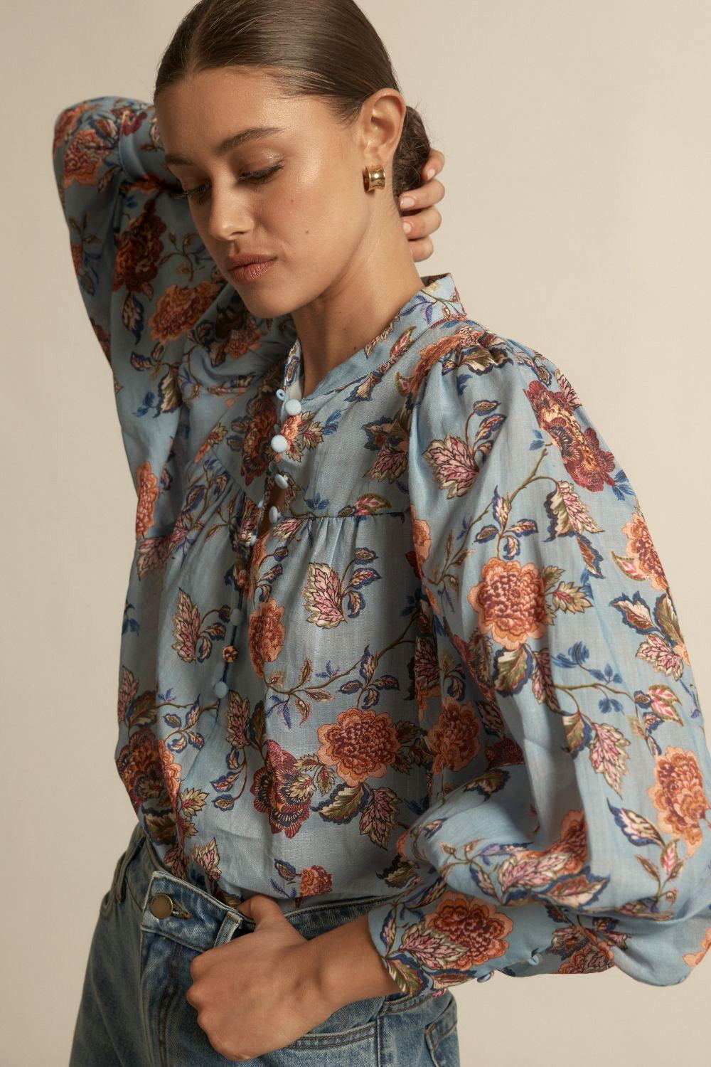 Woman wearing a floral blouse with a neutral background